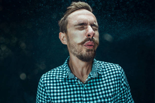istock Young handsome man with beard sneezing, studio portrait 992134398
