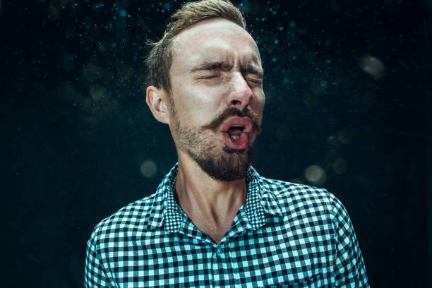 istock Young handsome man with beard sneezing, studio portrait 992136876