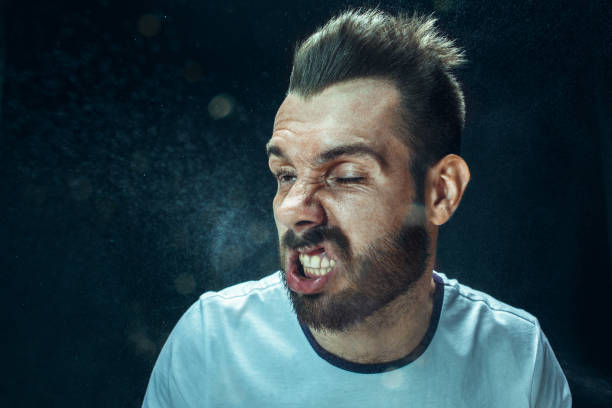 istock Young handsome man with beard sneezing, studio portrait 992136928