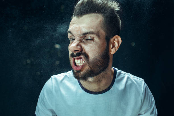 istock Young handsome man with beard sneezing, studio portrait 992137154