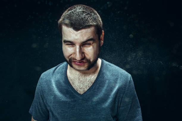 istock Young handsome man with beard sneezing, studio portrait 992137204