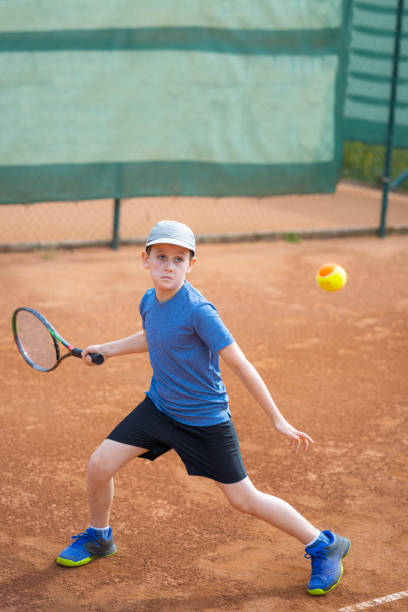 istock boy playing tennis on clay court 992137414