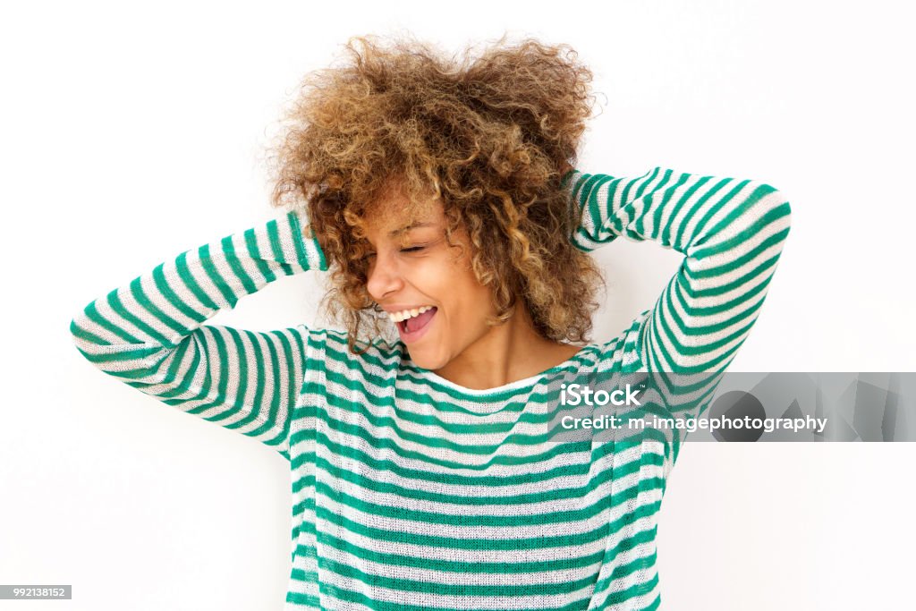 happy young black woman laughing with hand in hair Portrait of happy young black woman laughing with hand in hair Hand In Hair Stock Photo