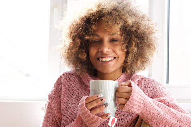 istock smiling young woman with cup of tea 992138258