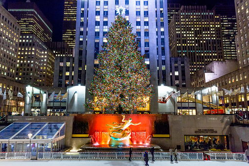 New York City, New York/United States - January 7, 2015: Brightly illuminated the Rockefeller Plaza ice skating rink filled with tourists and locals skating and watching, with a Christmas tree during the holiday season.