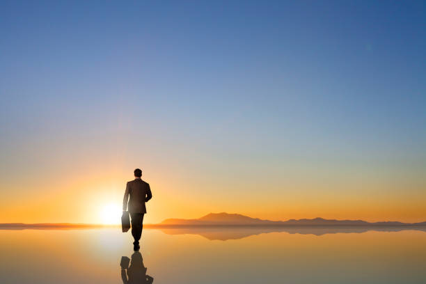 istock Businessman Walks Toward Sunset On Horizon 992145100