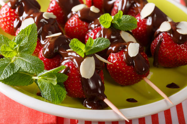 istock Skewers with strawberries decorated with chocolate, mint and almonds close-up. horizontal 992146484