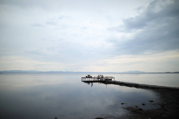 Sea and wooden pier with cloudy sky.