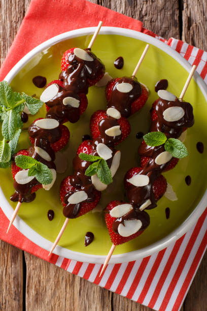 istock Strawberry on skewers with chocolate and almonds closeup. Vertical top view 992151120