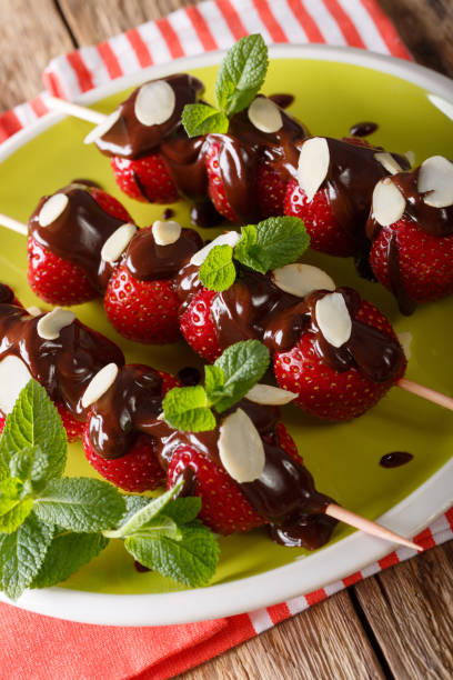 istock Skewers with fresh strawberries are decorated with chocolate, mint and almonds. vertical 992151252