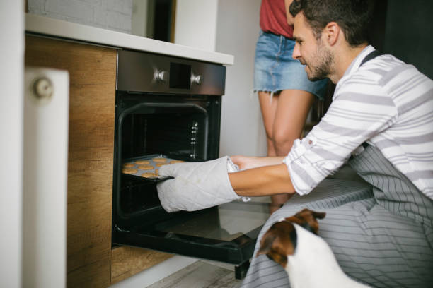 istock Young man checking food in oven low angle view 992182010