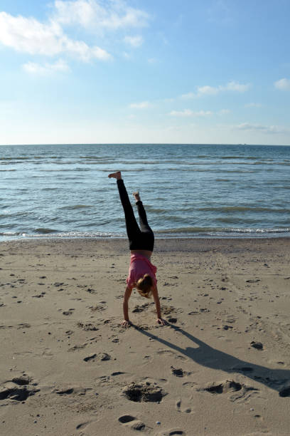istock Girls with the hand state on the sandy beach 992217314