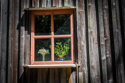 Window with old ceramic vase and wildflowers