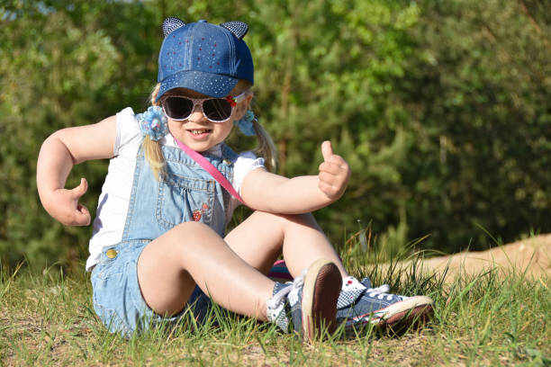 kleine mädchen spielen und lachen auf dem grünen rasen im sommer - naturkrause haare stock-fotos und bilder