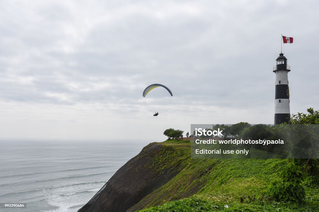 Paraglider by lighthouse on the coast of Lima, Peru A person paraglide by the lighthouse on the Costa Verde, an oceanside area of Lima, Peru. Airborne Sport Stock Photo