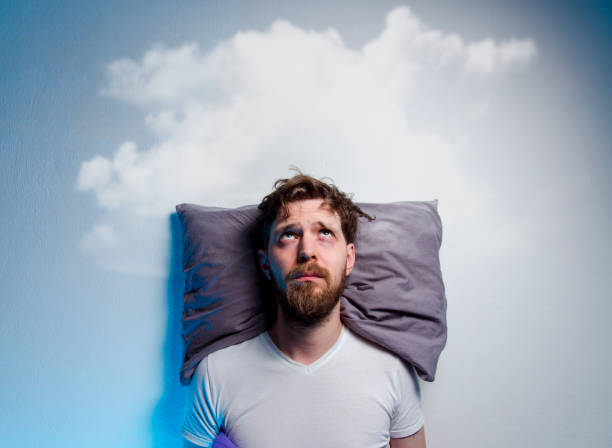 Man having problems/ insomnia, laying in bed Man having problems/ insomnia, laying in bed on pillow, looking up to gray cloud over his head, copy space insomnia photos stock pictures, royalty-free photos & images