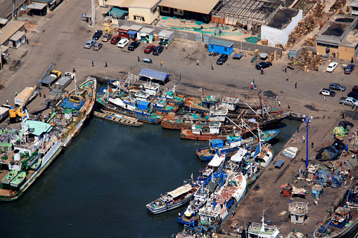 Fishing boats waiting while fishermen sell the catch of the day on the market. Meanwhile sharks and other catch of the day get offloaded from the boats (top left corner of the picture).