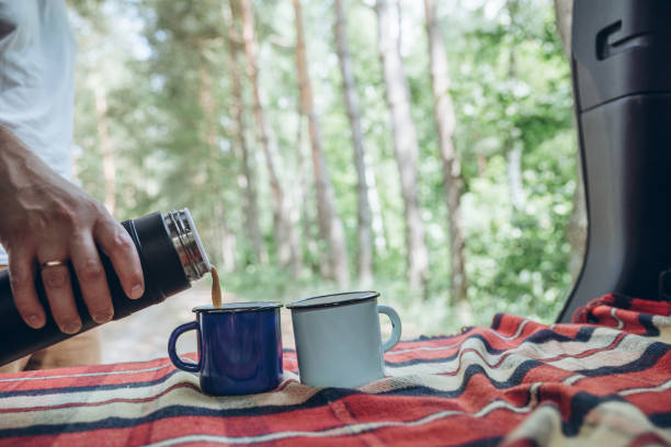 istock man hand pour on coffee into metal cups from thermos bottle. copy space 992303888