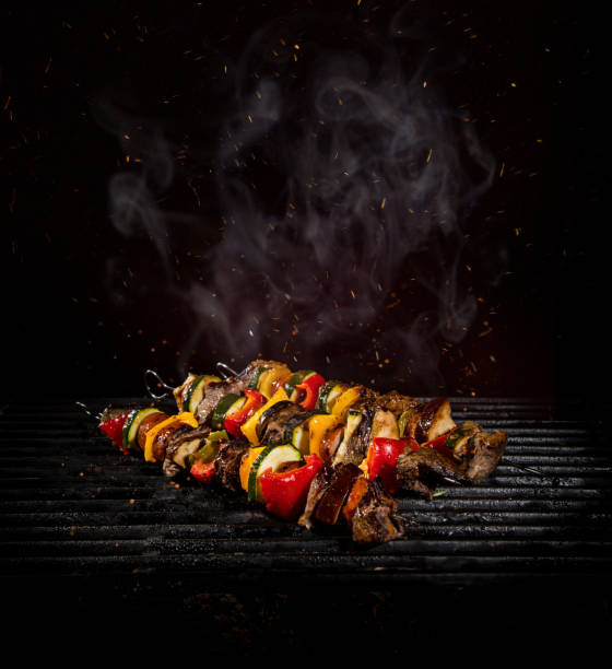 Chicken skewers on the grill with flames Tasty chicken skewers on iron cast grate with fire flames. skewer photos stock pictures, royalty-free photos & images