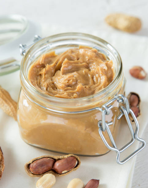 istock Glass jar with peanut butter on wooden background 992317200