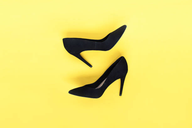 elegante moda scarpe nere tacchi alti su sfondo giallo. lay piatto, sfondo alla moda con vista dall'alto. look da blog di moda. - black heels foto e immagini stock