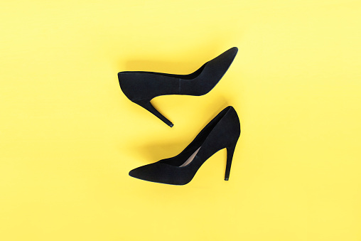 Stylish fashion black shoes high heels on yellow background. Flat lay, top view trendy background. Fashion blog look.