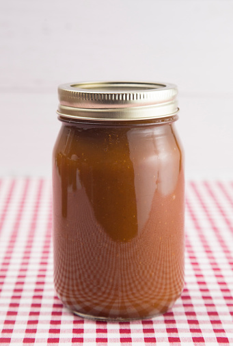 Apple Butter on a Red Gingham Table Cloth in a Home Canning Jar