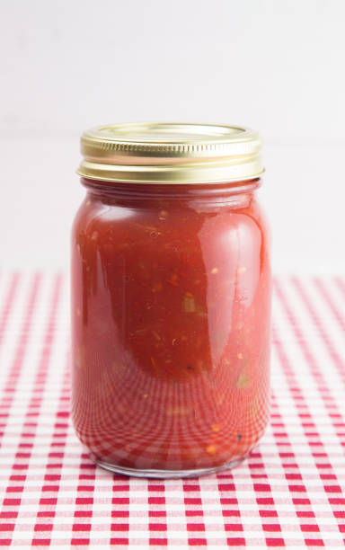 istock Salsa on a Red Gingham Table Cloth in a Home Canning Jar 992337744