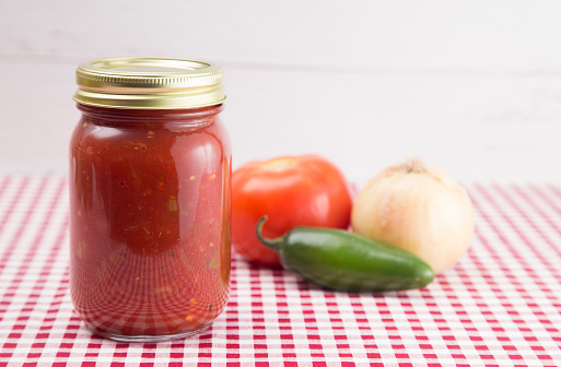 Salsa on a Red Gingham Table Cloth in a Home Canning Jar