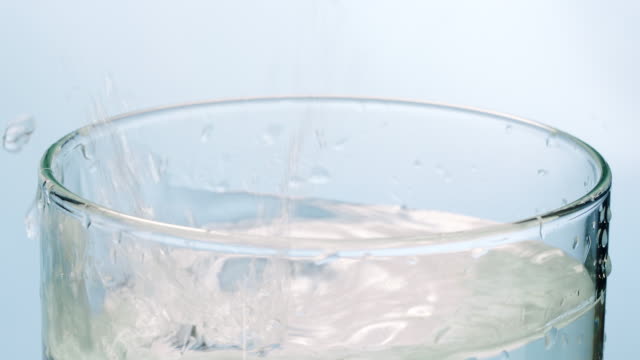 Ice cube and lemon slice falling down in water glass
