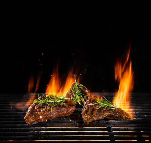 istock Beef steaks being grilled, isolated on black 992343860