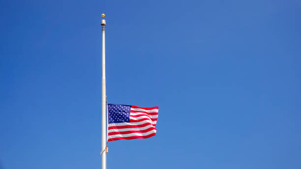 istock American Flag at Half Mast aka Half Staff Against Clear Blue Sky 992352520