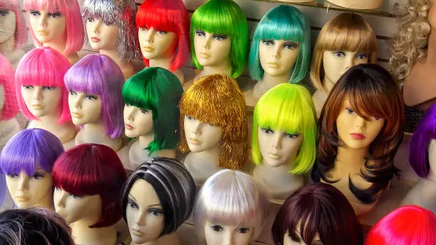 Mannequins wearing colorful wigs in a wig shop store window