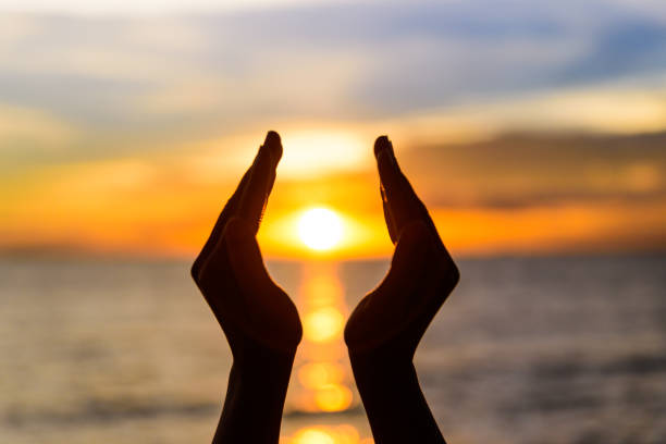 istock Woman hands holding the sun during sunrise or sunset. 992396530