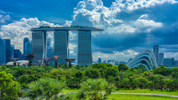 vue du parc vers l’emblématique hôtel et jardins tropicaux - gardens by the bay photos et images de collection