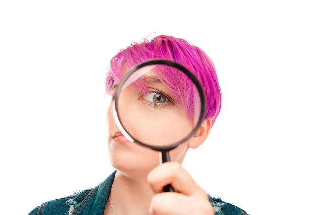 female face with magnifying glass lens on her green grey eye - magnifying glass lens holding europe imagens e fotografias de stock