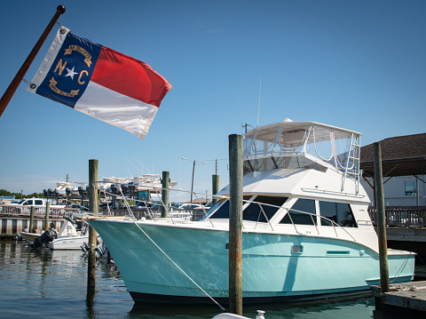 The state flag of North Carolina waves proudly at a coastal marina.