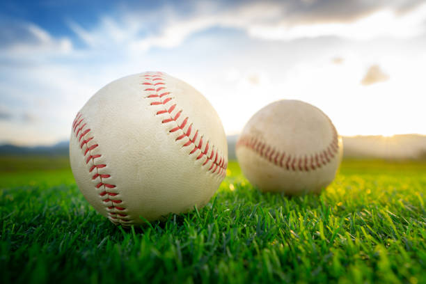 istock Close up baseball on the green grass background at sunset. 992427544