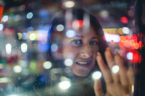 istock Young woman looking city lights through glass. 992443040