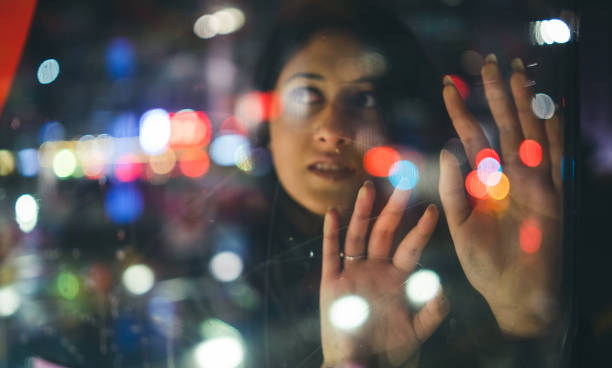 istock Young woman looking city lights through glass. 992443048