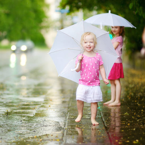 istock Two cute little sisters on a rainy summer day 992465230