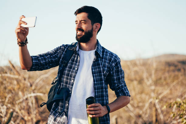 istock Man with backpack taking selfie with his mobile phone during desert hike 992468902