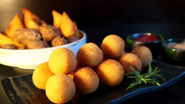 istock Brazilian snack bolinha de queijo, deep fried balls stuffed with cheese on dark background 992489482
