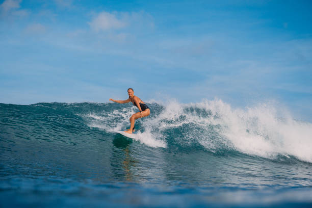 istock Surfer woman with surfboard on ocean wave. 992516562