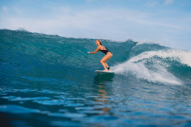istock Surfer woman at surfboard ride on ocean wave. 992516864