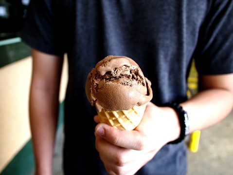 Photo of a young man holding a chocolate ice cream up to his face