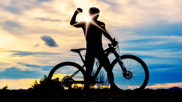 silhouette of man and bicycle on sunset sky