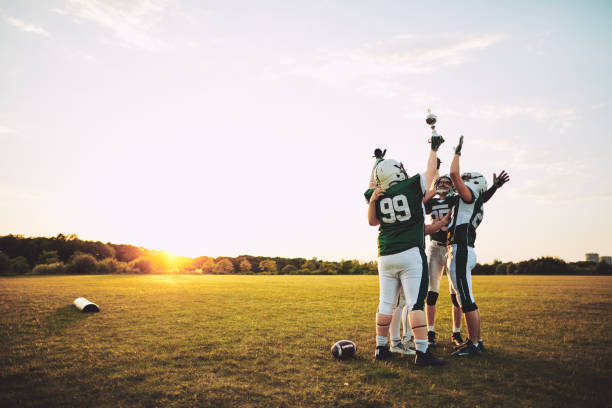 fußball-nationalmannschaft feiert mit ihrer trophäe auf einem feld - football player american football athlete sport stock-fotos und bilder