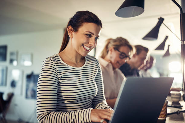 istock Smiling young designer working online at a table with coworkers 992570786