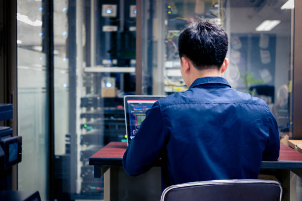 Technicians using laptop while analyzing server in server room stock photo